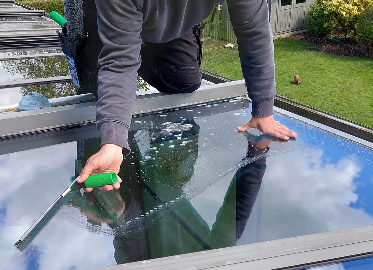 Homme nettoyant les vitres d'une pergola